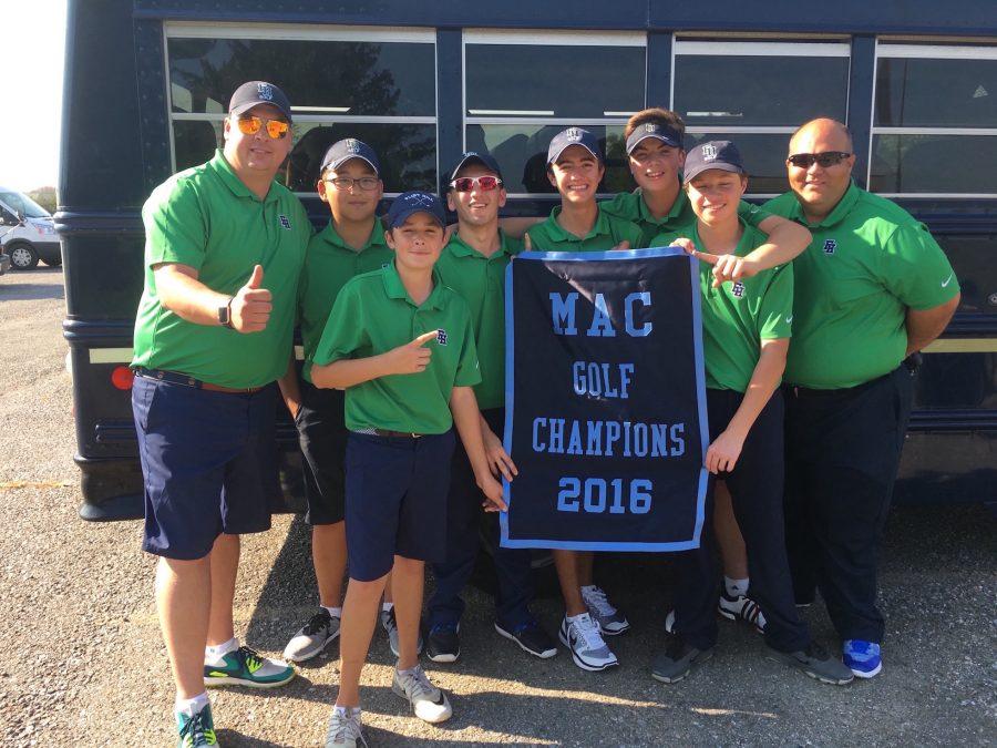 The golf team shows their first-place MAC championship win with their fingers in front of the bus.